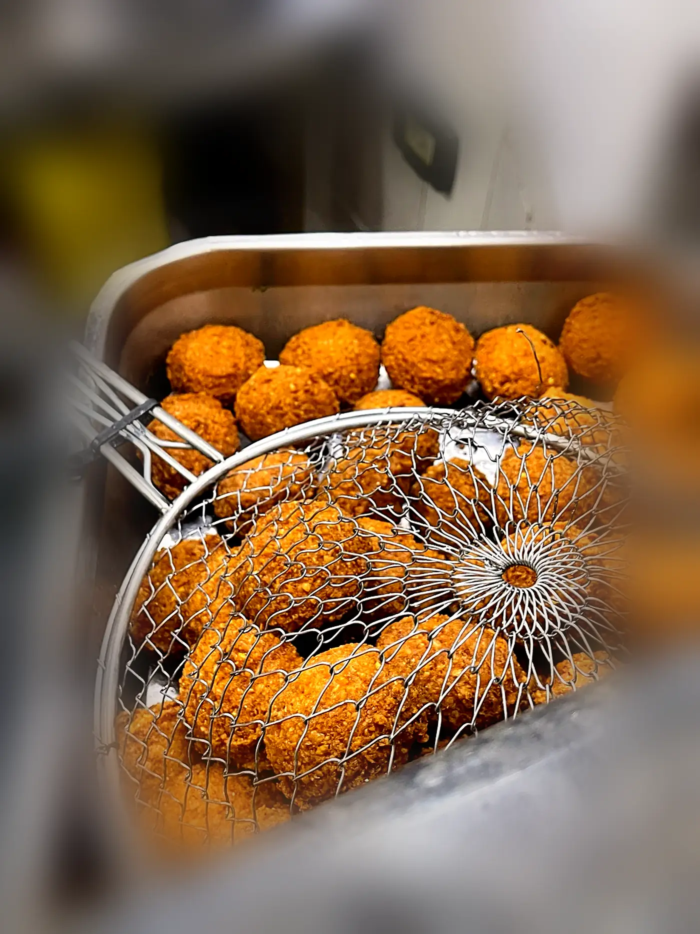 Freshly cooked falafel lifted out in a wire skimmer